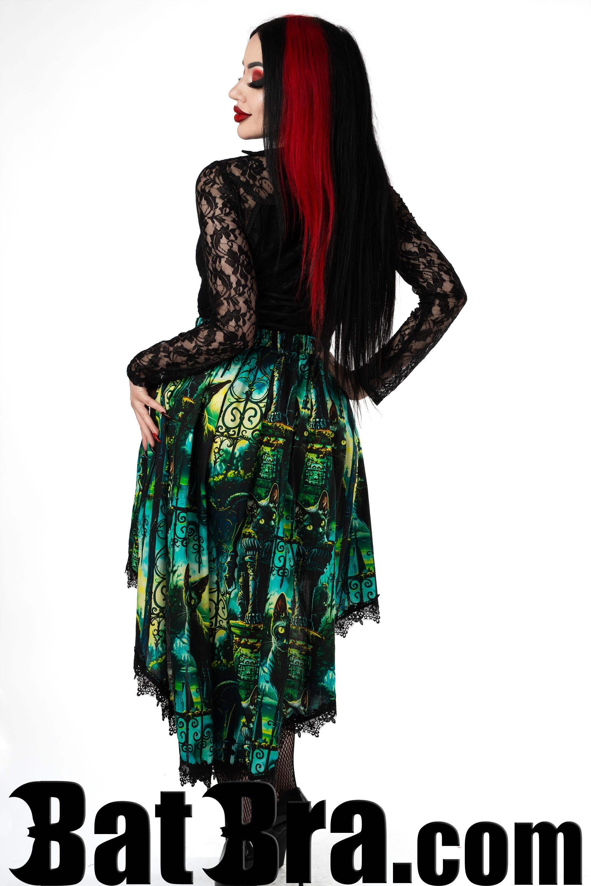 Back view of women's printed asymmetrical skirt with cat design in blues greens and yellows showing longer back of skirt and a black lace trim